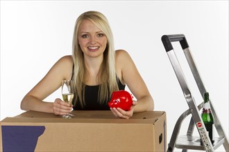 Young woman with a piggy bank and a moving box