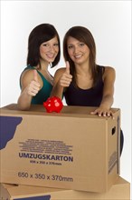 Two young woman with moving boxes and a piggy bank