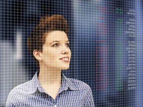Business woman with a punk hairstyle in front of a stock exchange board
