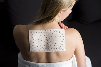 Young woman suffering from back pain has applied a heat plaster