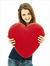 Young woman holding a heart-shaped pillow