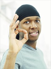 Dark-skinned man wearing a bandana and making an OK sign