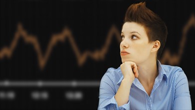 Business woman with a punk hairstyle in front of a stock exchange board