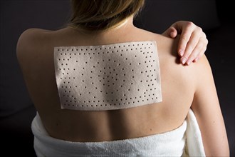 Young woman suffering from back pain has applied a heat plaster
