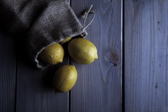 Lemons in a jute sack on wooden boards
