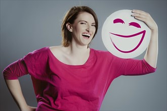 Smiling young woman holding a smiley face