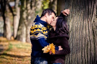 Young couple kissing in a park in autumn