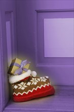 Woolly slipper with a Norwegian pattern and presents standing outside a front door