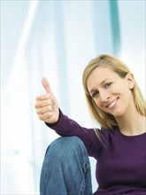 Young woman making a thumbs up gesture
