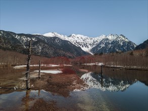 Snow-covered Japanese Alps reflected in Lake Taisho Pond