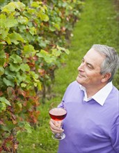 Winemaker or vintner holding a glass of wine in his vineyard