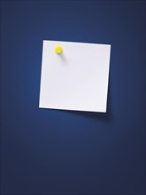 White note with a yellow pin on a blue wall