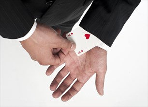Man wearing a suit pulling an ace of hearts out of his sleeve