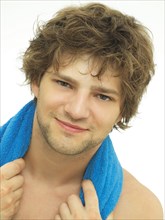 Young man with a blue towel wrapped around his shoulders