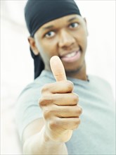Dark-skinned man man wearing a bandana and making a thumbs up gesture