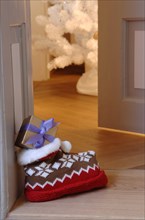 Woolly slipper with Norwegian pattern and present outside an open door
