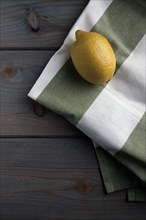 Lemon on a kitchen towel on a wooden background