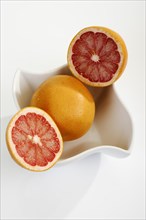 Ruby grapefruit cut open in porcelain bowl