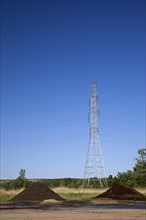 Mounds of topsoil and a hydro electricity transmission tower in a commercial sandpit