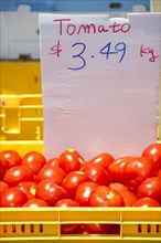 Tomatoes in a yellow basket with a price tag