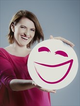 Smiling young woman holding a smiley face