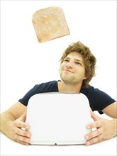 Young man looking at a slice of toast as it pops out of a toaster