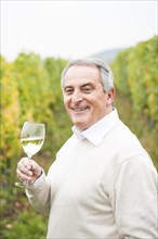 Winemaker or vintner holding a glass of wine in his vineyard