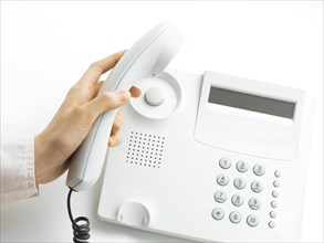Woman picking up the handset of a telphone