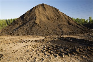 Heavy tire tracks and a mound of topsoil in a commercial sandpit