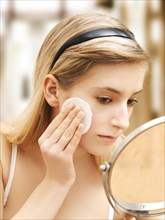 Young woman cleaning her face with a cotton pad