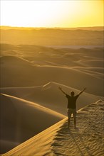 Man enjoying the sunset in the giant sanddunes of the Sahara