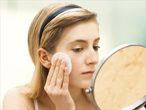 Young woman cleaning her face with a cotton pad