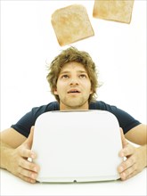 Young man looking at slices of toast as they pop out of a toaster