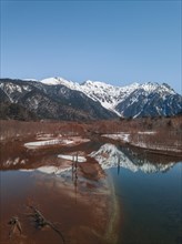 Snow-covered Japanese Alps reflected in Lake Taisho Pond