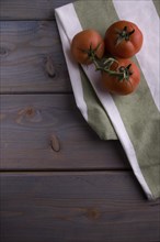 Tomatoes on a kitchen towel on a wooden background