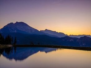 Mountain silhouettes reflected in an artificial mountain lake at sunset