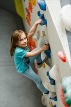 Girl bouldering on a climbing wall in a hall