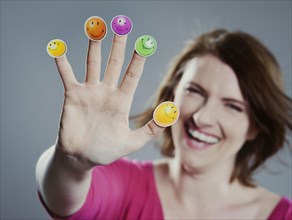 Smiling young woman with smiley face stickers on her fingers