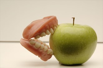 Dentures biting into a green apple