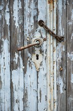 Door handle with a rusty chain on a weathered wooden door