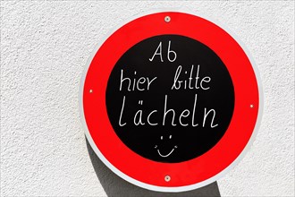 Traffic sign with inscription From here please smile and smiley