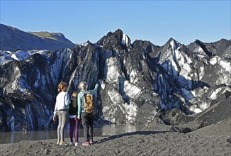 Mother with two children looks at the Solheimajokull glacier