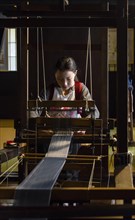 Japanese young woman weaving at the loom