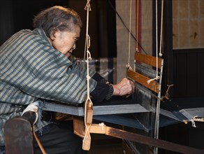Old Japanese woman weaving at the loom