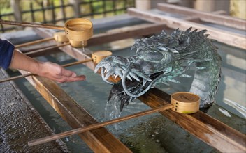 Ritual washing of hands at a sink with dragon figure at a Japanese temple