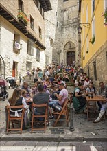 People eating in a street restaurant in front of Church of San Miguel