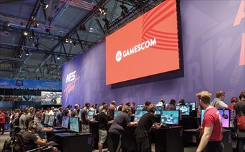 Visitors play video games under the gamescom logo at gamescom