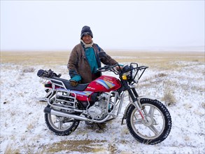Old man with his motorcycle in a blizzard