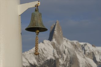 Ship bell in front of mountain scenery
