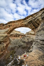 Tourist sits under rock arch